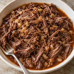 Square view of finished shredded barbacoa in a cream bowl.
