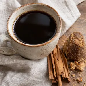 Square view of café de olla with cinnamon bark and piloncillo.