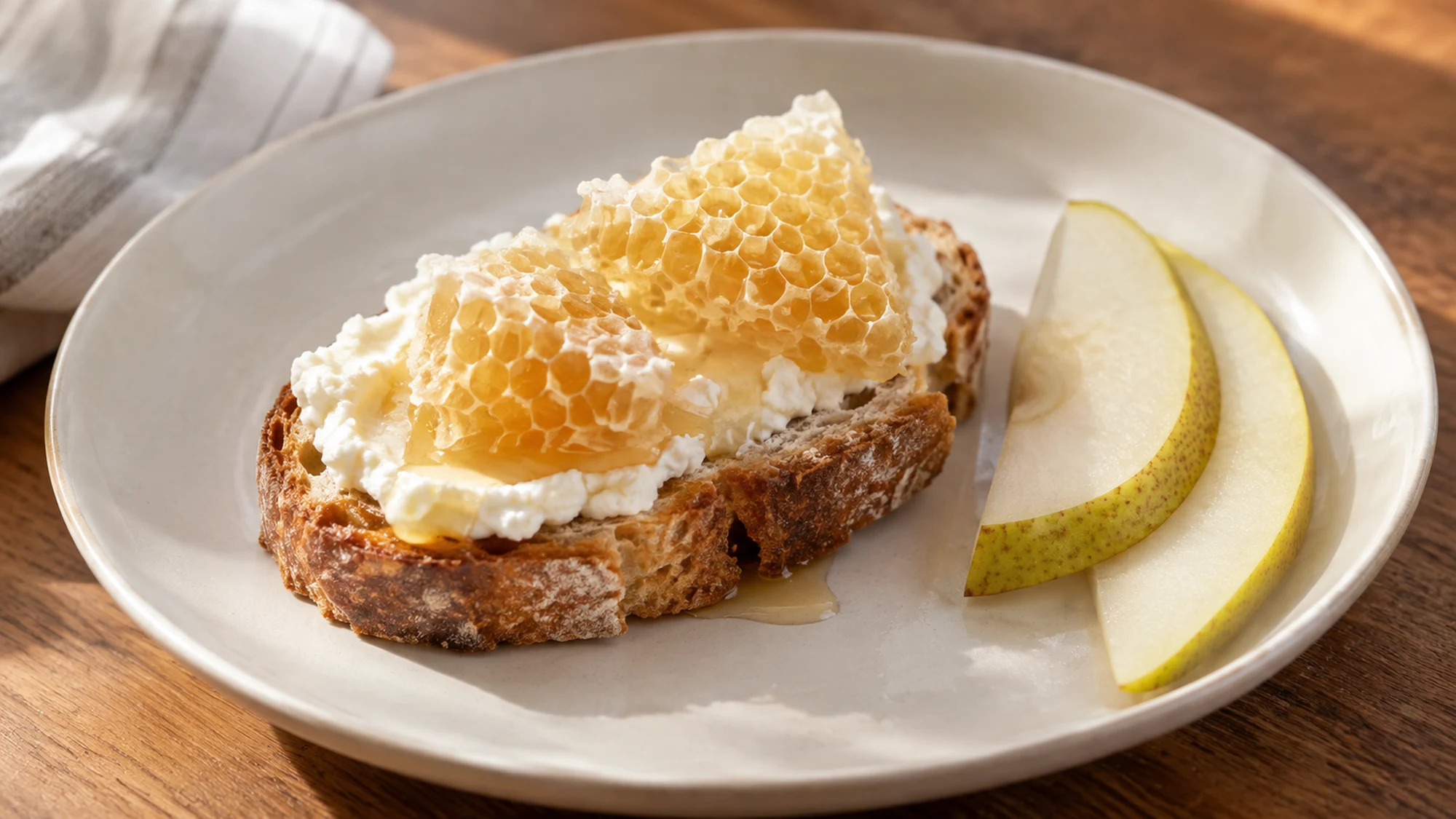 Honey comb served on toast with white cheese and pear slices.