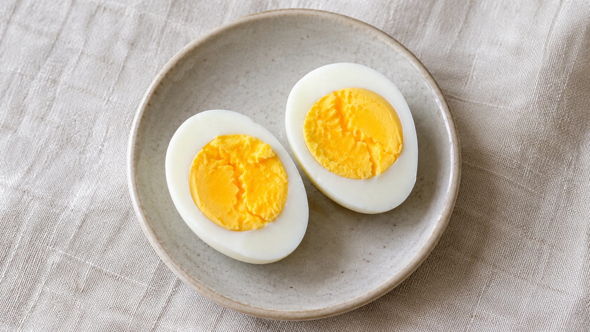 Two halves of one hard-boiled egg showing the firm white and golden yolk