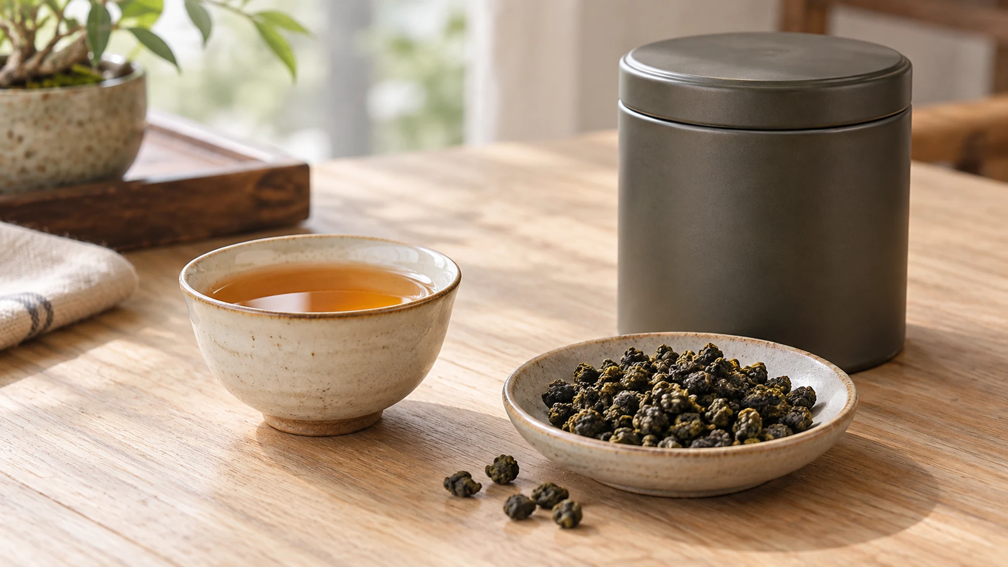 Amber oolong tea beside a closed tea tin and dry rolled leaves