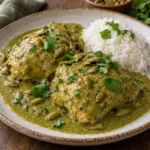 Square image of chicken thighs coated in pumpkin seed sauce with rice.