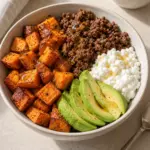 Square view of sweet potato ground beef bowl with roasted potato cubes, cottage cheese, avocado and a little hot honey.