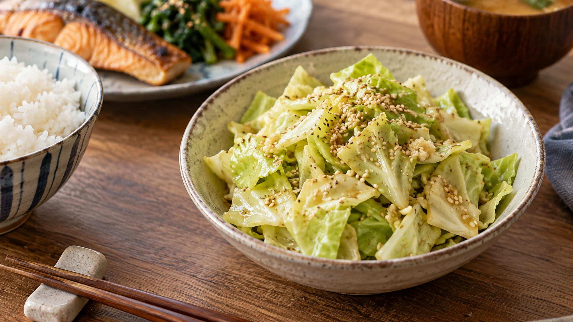 A small bowl of yamitsuki cabbage beside rice and a simple Japanese-inspired dinner.