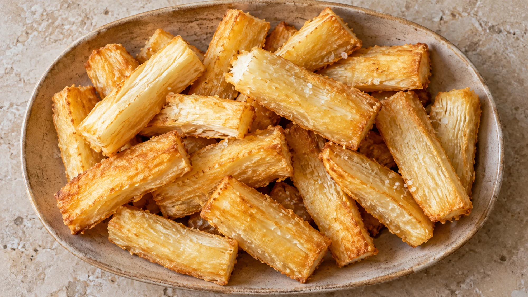 Overhead view of plain golden cassava fries on a ceramic platter