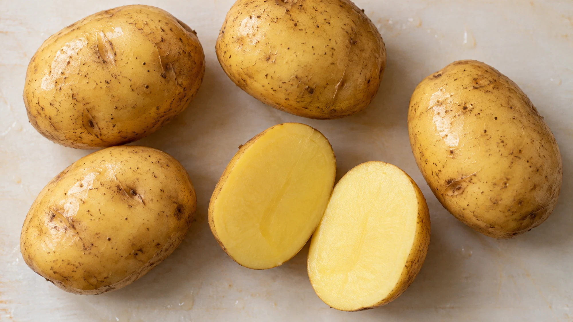 Overhead view of whole Yukon Gold potatoes and two halves showing yellow flesh